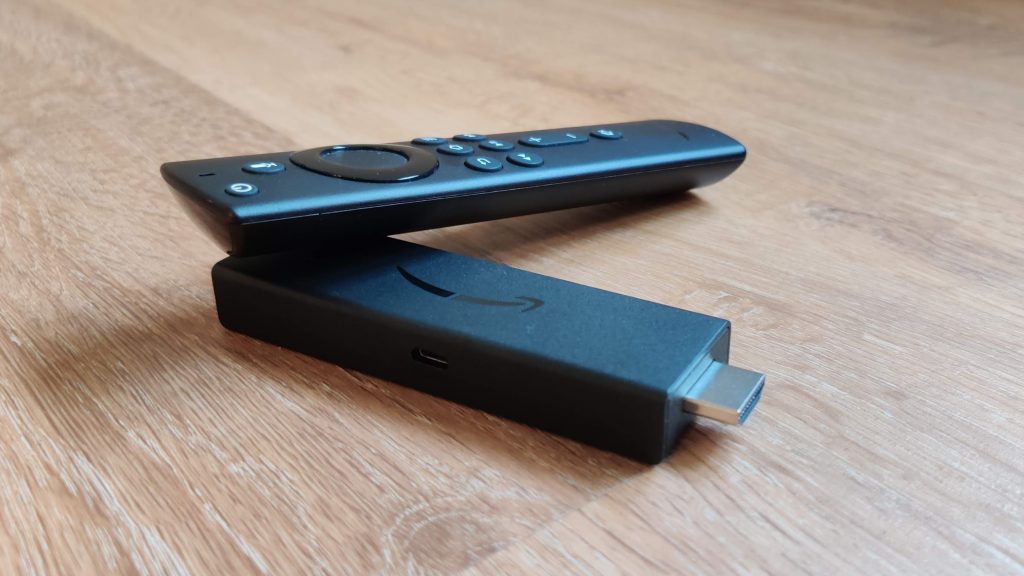 der FireTV Stick 4K liegt mit der zugehörigen Fernbedienung auf Holz